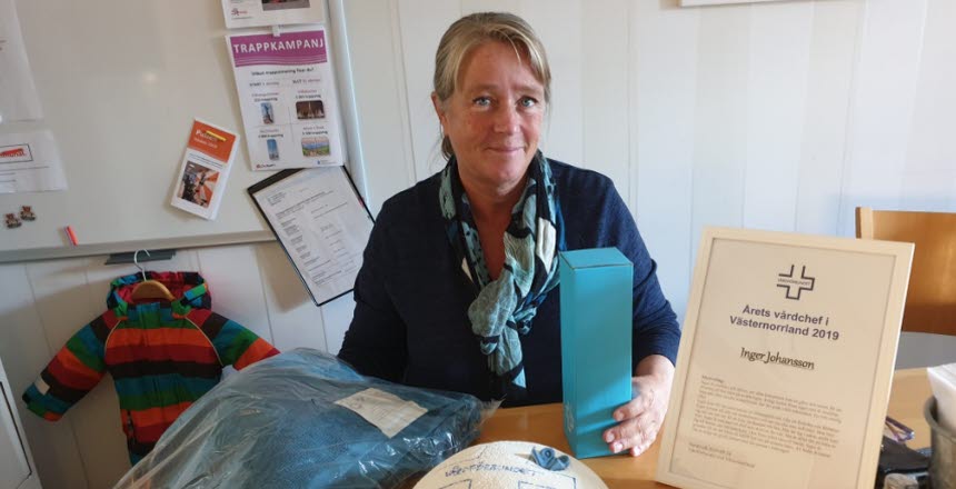 Årets vårdchef Inger Johansson sitter vid ett bord med ett diplom och en tårta framför sig