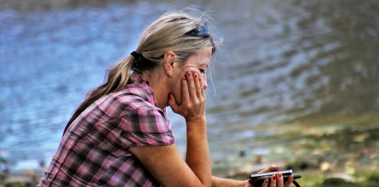 Kvinna som sitter vid en sjö och tänker