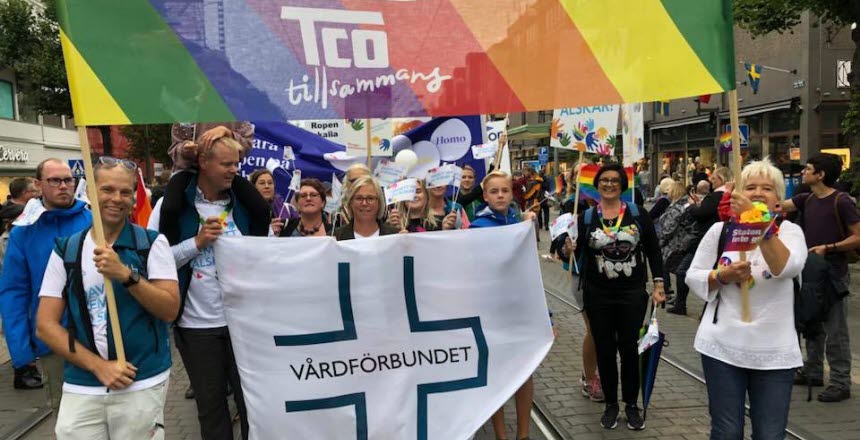 Vårdförbundet går i parad med en Vårdförbundet-flagga och en regnbågsfärgad banderoll med text