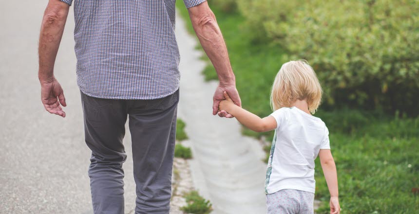 Man går på en väg med en flicka i handen. bakifrån, rygg, hand, hand i hand, flicka, man, gubbe, liten, sommar, barn, fritid, pensionär