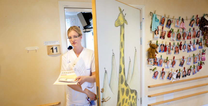Barnsjuksköterska på väg ut ur rum på barnavdelningen på SÖS. På dörren är en giraff målad.