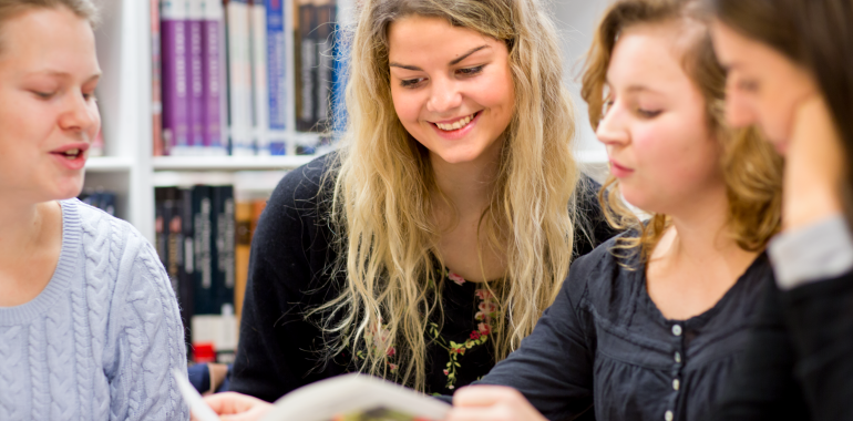 Fyra studenter på bibliotek