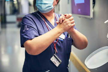 Sjuksköterska som bär munskydd spritar händer
