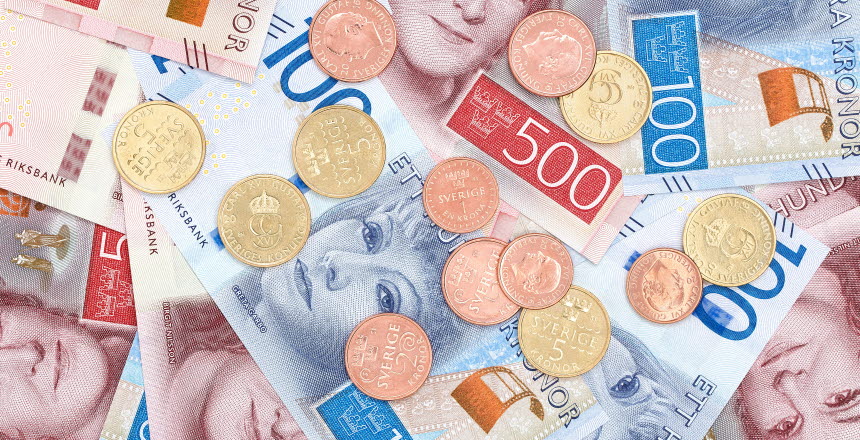 Pengar som ligger i en utspridd hög med både sedlar och mynt