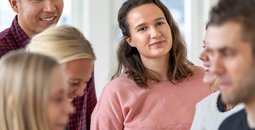 Studenter som står i en grupp, en tjej tittar in i kameran