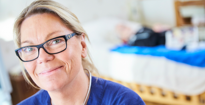 Porträtt på sjuksköterska hemma hos en av de äldre på äldreboendet.
