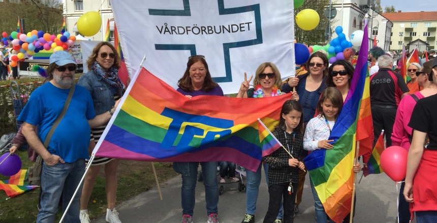 Bild från Pride paraden i Växjö människor som håller Vårdförbundets banderoll samt en Prideflagga från TCO