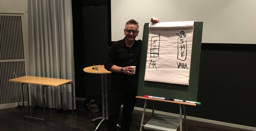 Föreläsare Torkild Sköld står och lutar sig på ett blädderblockstativ
